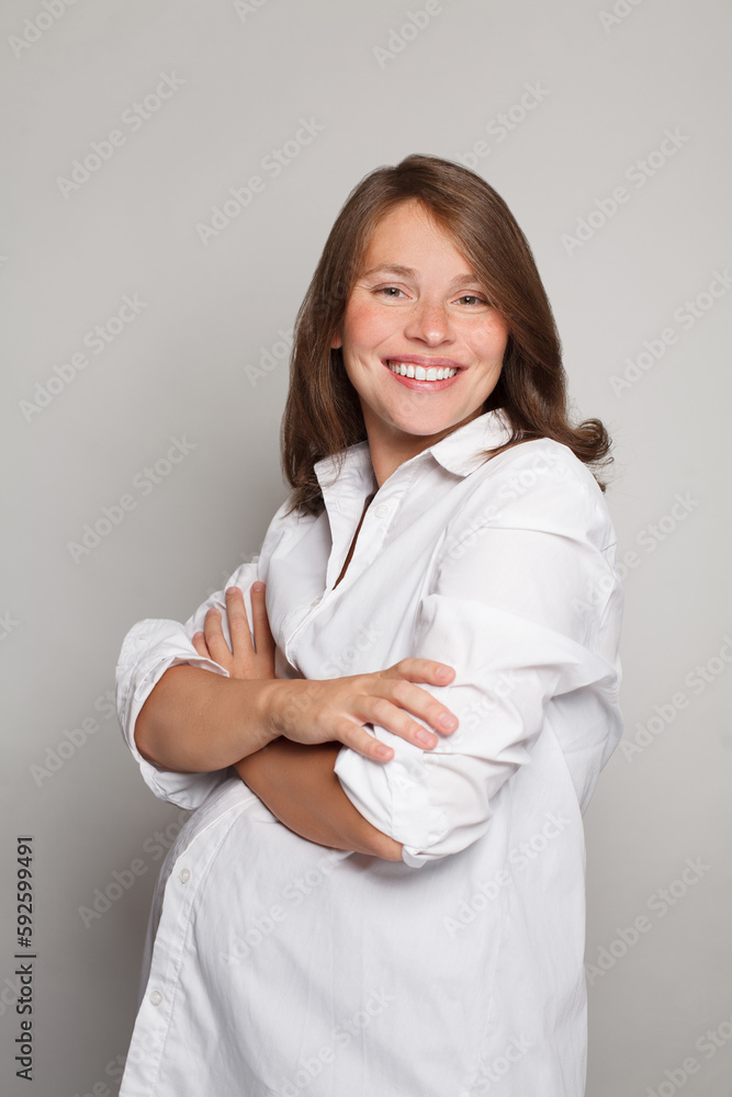 Happy successful pregnant woman in white shirt smiling against white studio wall background Happy successful pregnant woman in white shirt smiling against white studio wall background