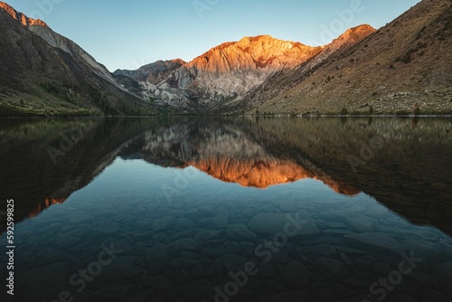 Beautiful shot of a lake reflecting the mountains surrounding it © Nikolay Zlatev/Wirestock Creators