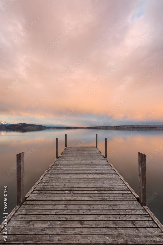 Vertical shot of a pier and a scenic seascape at sunset in Zug, Switzerland