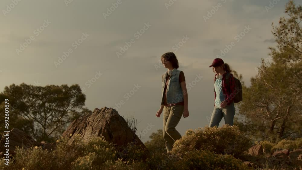 Modern children hiking trip in mountains. Teenagers with backpacks at sunset outdoors Modern children hiking trip in mountains. Teenagers with backpacks at sunset outdoors
