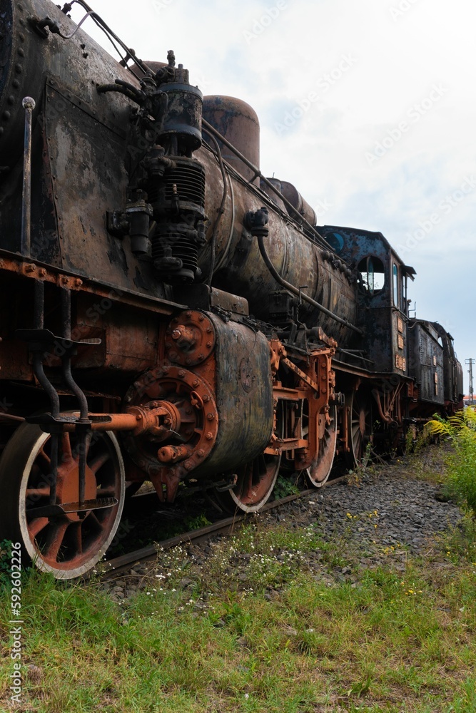 Fototapeta premium Vertical shot of steamed locomotive in a junkyard