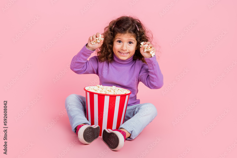 Full length photo of excited funky little child dressed purple pullover eating throwing pop corn isolated pink color background Full length photo of excited funky little child dressed purple pullover eating throwing pop corn isolated pink color background