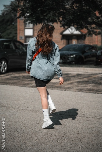 Happy caucasian casual girl wearing jean jacket and short crossing the street