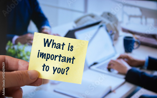 Male hand holding sticky note written What is important to you?