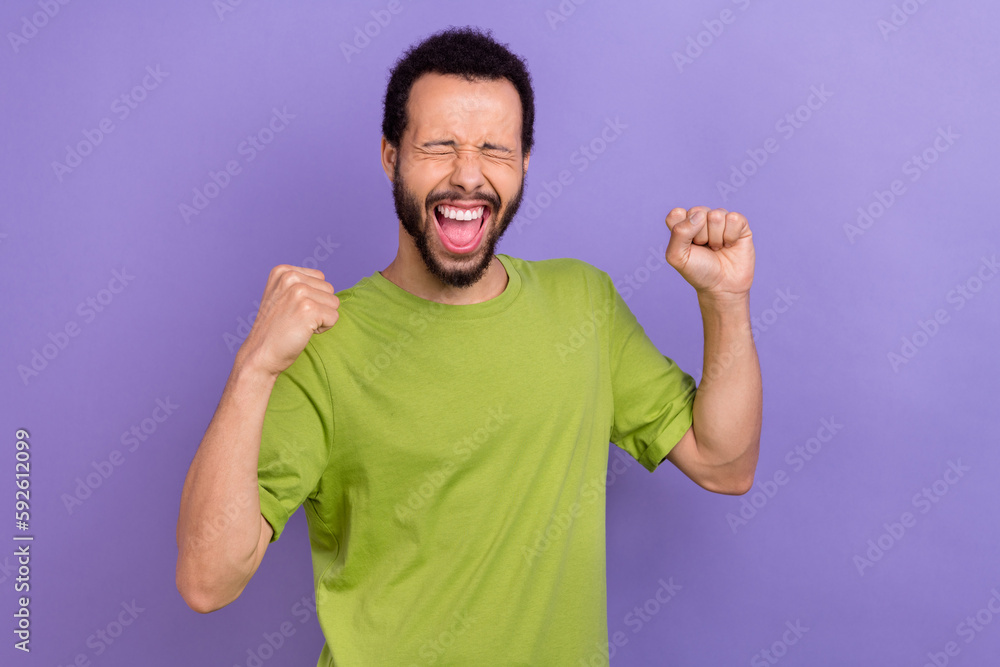 Portrait of delighted overjoyed handsome man closed eyes raise fists shout yes hooray isolated on purple color background Portrait of delighted overjoyed handsome man closed eyes raise fists shout yes hooray isolated on purple color background