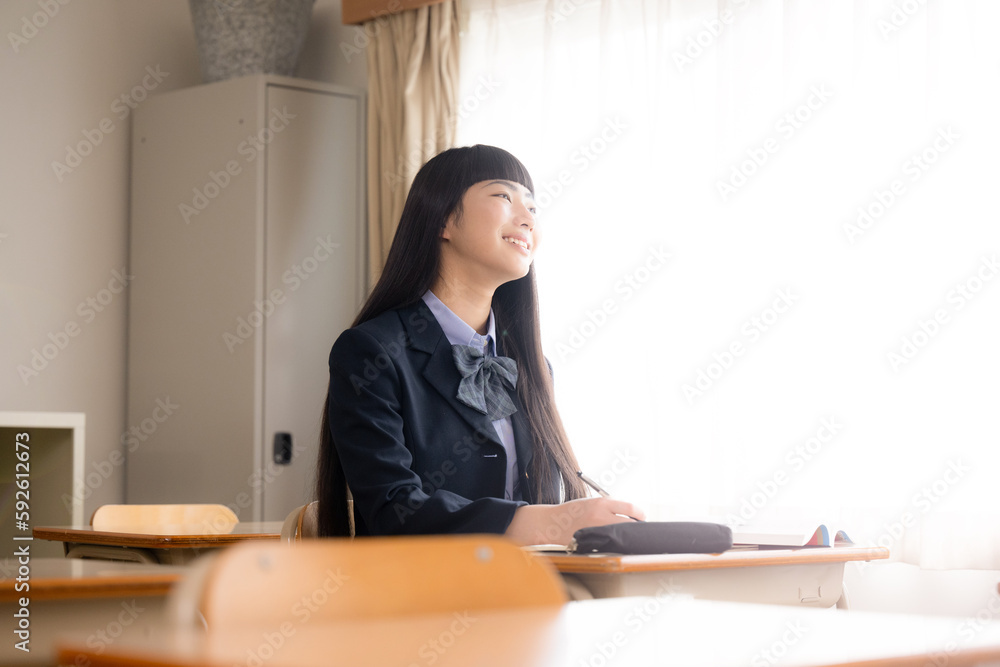放課後の教室で夕日に照らされながら勉強している見上げる女子中学生や高校生のイメージ 青春 放課後の教室で夕日に照らされながら勉強している見上げる女子中学生や高校生のイメージ 青春
