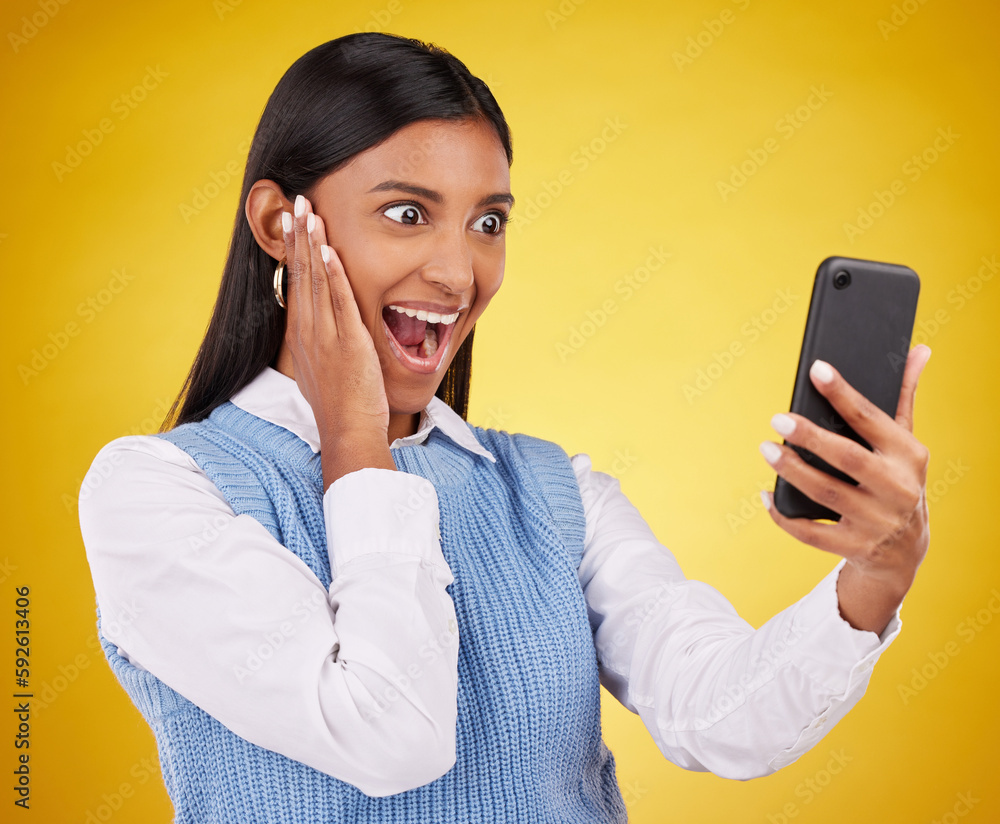 Phone surprise, online news and happy woman shocked over mobile notification, app promotion or wow discount. Reading OMG info, cellphone announcement and excited studio female on yellow background Phone surprise, online news and happy woman shocked over mobile notification, app promotion or wow discount. Reading OMG info, cellphone announcement and excited studio female on yellow background