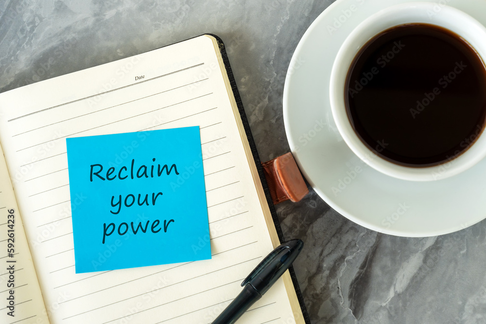 Cup of coffee and adhesive note on notepad with text reclaim your power Cup of coffee and adhesive note on notepad with text reclaim your power