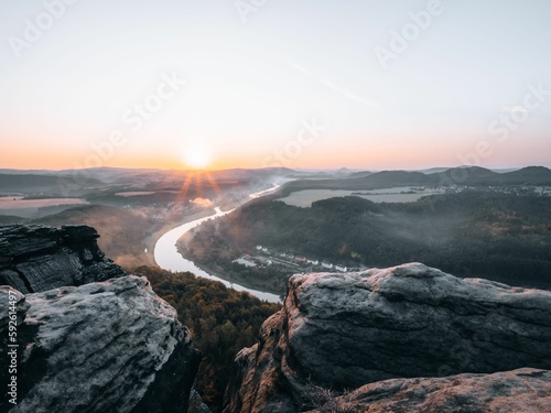 Beautiful shot from the edge of a cliff to a river during the sunset © Steffen Zenker/Wirestock Creators