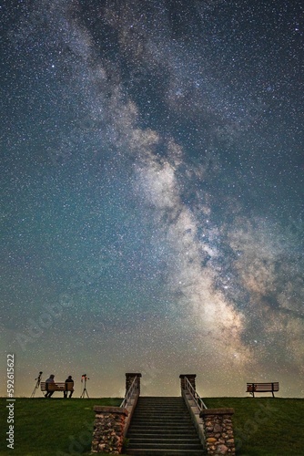 фотографія Vertical shot of people on the bench against the background of the starry sky