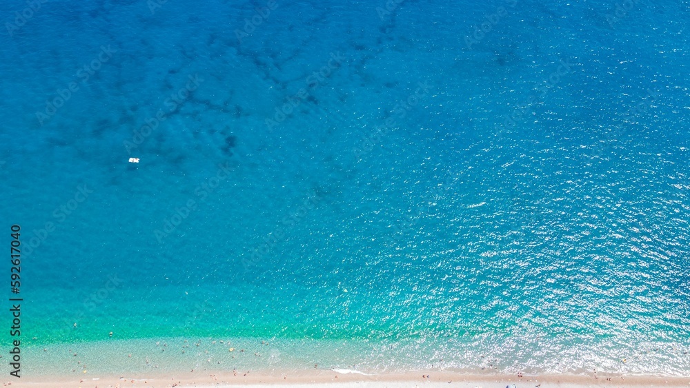 Obraz premium Aerial view of the bright blue sea water at a sandy beach