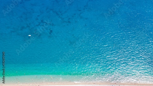 Aerial view of the bright blue sea water at a sandy beach