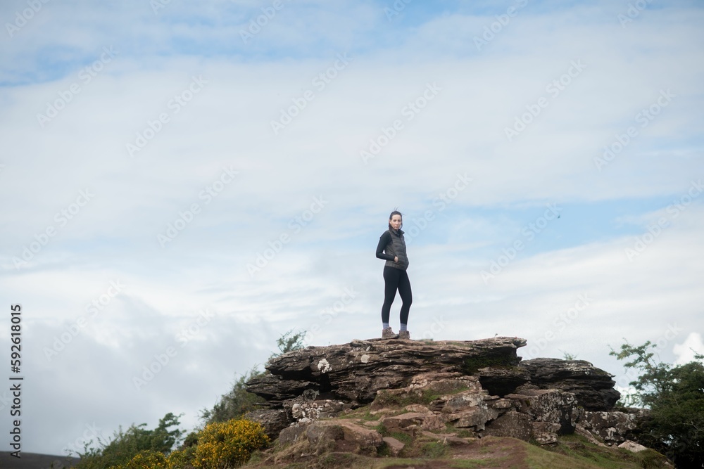 Female on a top of a mountain against cloudy sky