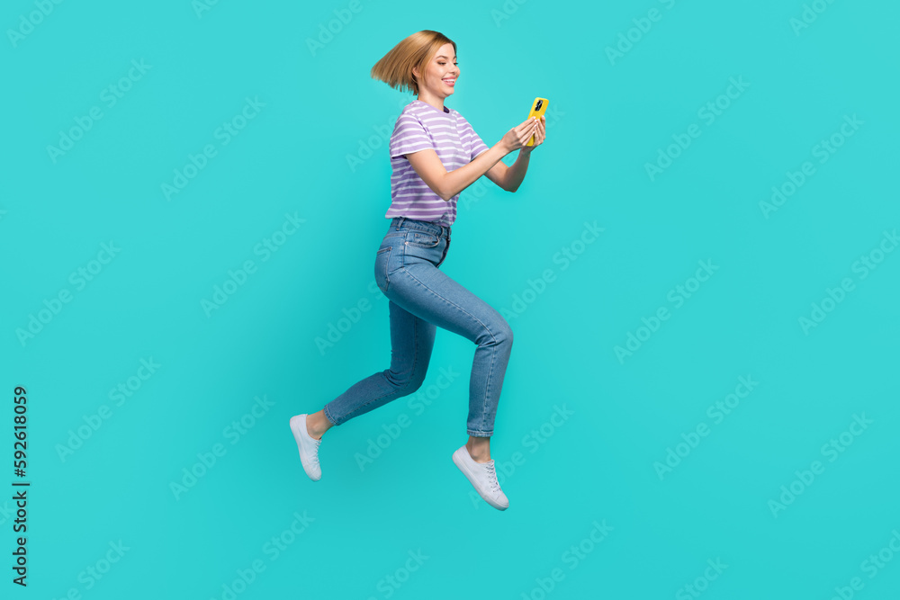 Full size photo of cheerful pretty woman bob hairdo striped t-shirt hurry run look at smartphone isolated on teal color background Full size photo of cheerful pretty woman bob hairdo striped t-shirt hurry run look at smartphone isolated on teal color background