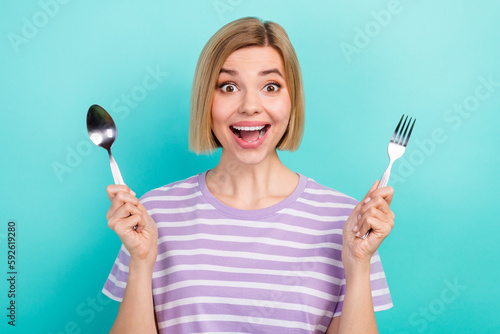 Photo of funny impressed girl short hairstyle striped t-shirt hold spoon fork staring open mouth isolated on turquoise color background