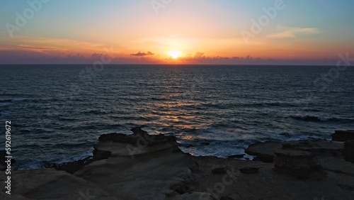 Aerial view over beautiful ocean during sunset. Top view to the ocean in summer day while sunset - closeup. Drone view of a Scenic slow motion ocean waves. Beautiful sunrise over ocean
