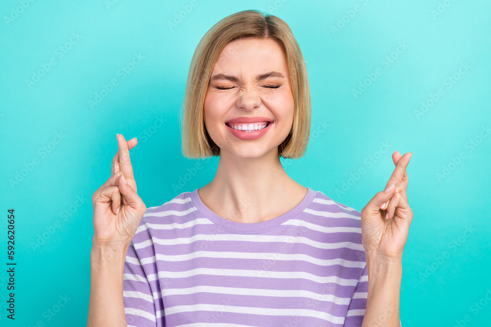 Portrait of young pleading blonde hair crossed her fingers wear striped t-shirt want pass her exam isolated on aquamarine color background Portrait of young pleading blonde hair crossed her fingers wear striped t-shirt want pass her exam isolated on aquamarine color background