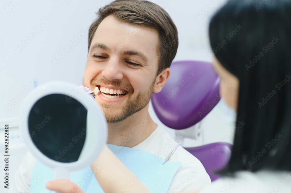 Dentist checking and selecting color of young man's teeth. Dentist checking and selecting color of young man's teeth.
