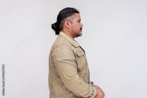 Side view of a man with long tied hair and in a jacket detained and handcuffed. Isolated on a white background.