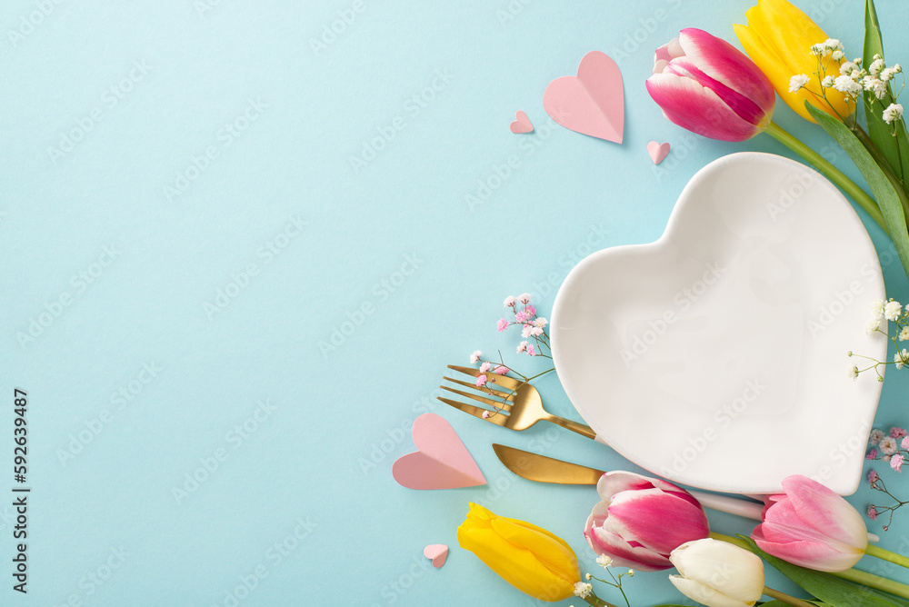Mother's day trendy table concept. Top view of empty plate, cutlery, tulips and decorative hearts on pastel blue background. Ideal copyspace for advertising or text