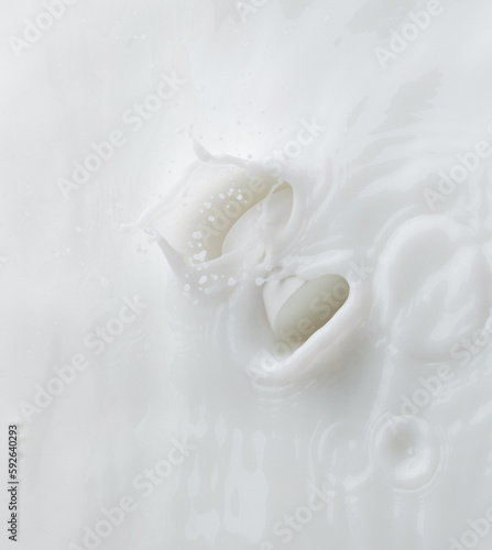 Cosmetic container white lotion droplet fly splashing. Milk lotion pour float to cosmetic bottle. Moisturizer lotion explosion spill. White background isolated high speed shutter freeze top view