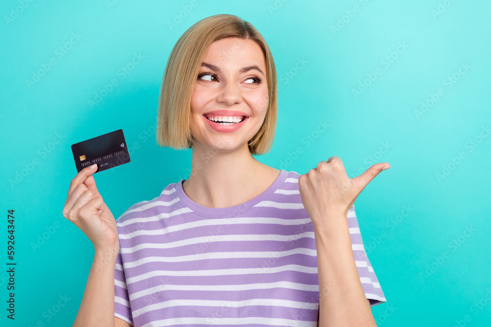 Portrait of satisfied woman short haircut stylish t-shirt indicating look empty space offer hold card isolated on teal color background Portrait of satisfied woman short haircut stylish t-shirt indicating look empty space offer hold card isolated on teal color background