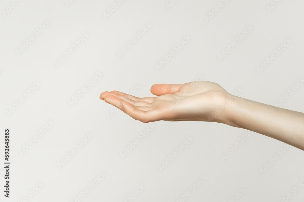 female hand holding or showing something on gray background