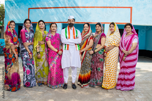Indian man politician standing cross arms with group of traditional women. Concept of election and vote.