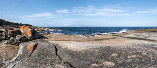 Orange-hued granite rocks in the Bay Of Fires on the northeastern coast of Tasmania in Australia. Panoramic view