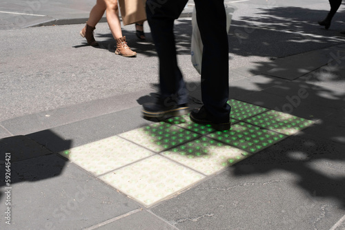 Pedestrian crossing lights embedded in the pavement for phone zombies that never look up at pedestrian crossings in Melbourne, Australia. Bright green square glowing tiles in action © Henk Vrieselaar