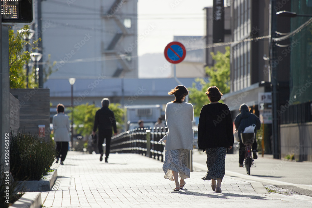 京都の朝の街を散歩している若い女性の後姿