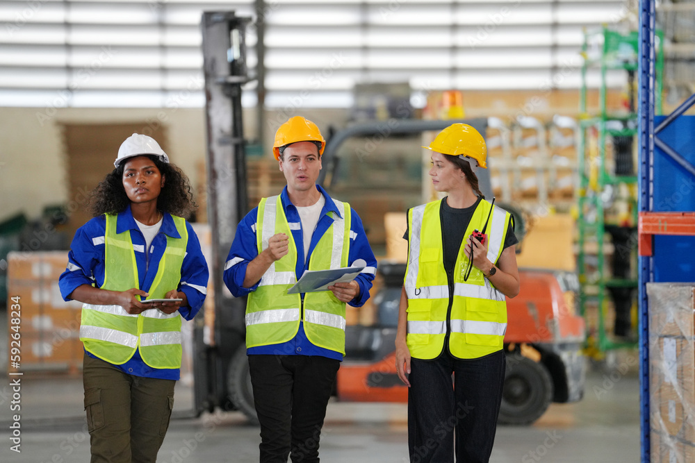 Multiethnic industrial workers checking their logistic lists while working with transportation of goods in warehouse Multiethnic industrial workers checking their logistic lists while working with transportation of goods in warehouse