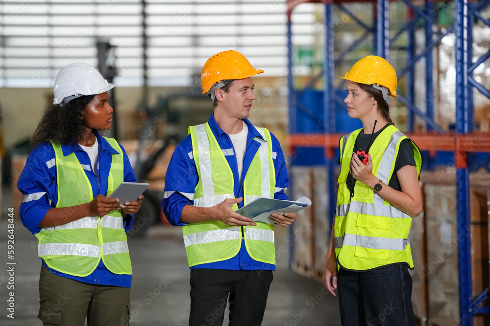 Multiethnic industrial workers checking their logistic lists while working with transportation of goods in warehouse Multiethnic industrial workers checking their logistic lists while working with transportation of goods in warehouse