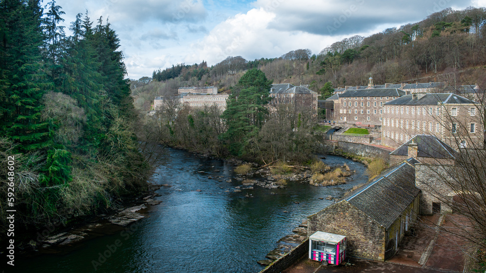 Fototapeta premium Panoramic view of New Lanark UNESCO World Heritage Site in Lanarkshire, Scotland, UK. The River Clyde flows through Robert Owen's famous industrial village.