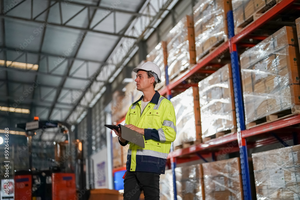 Multiethnic industrial workers checking their logistic lists while working with transportation of goods in warehouse Multiethnic industrial workers checking their logistic lists while working with transportation of goods in warehouse