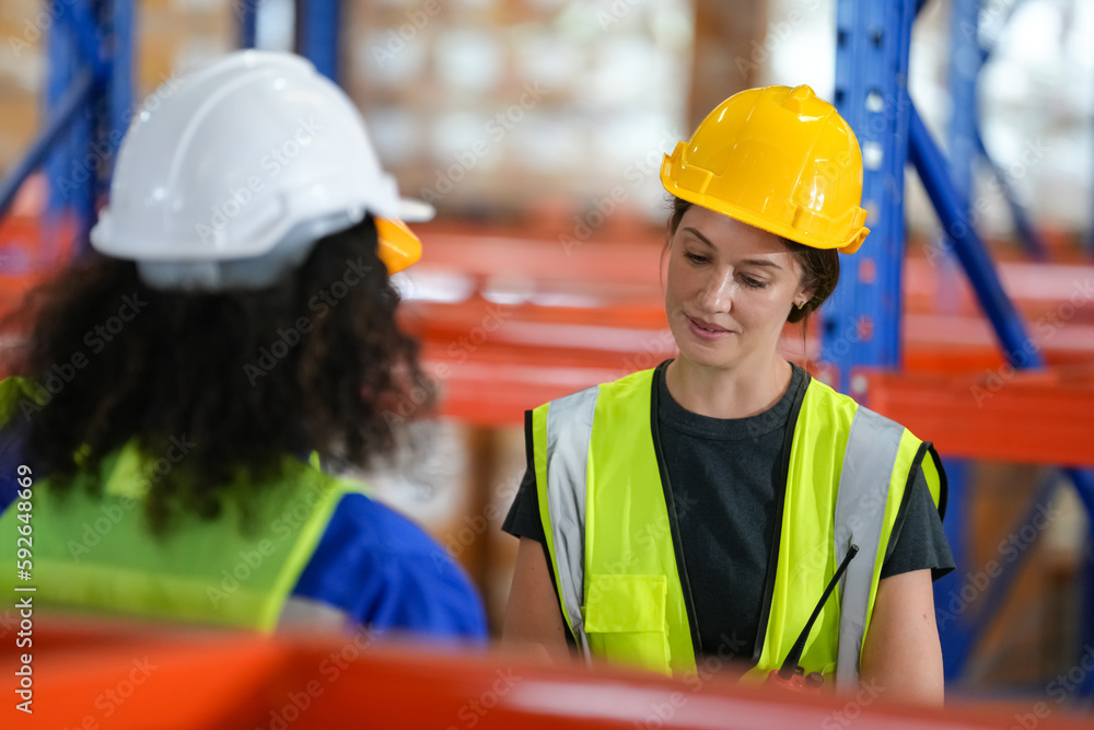 Multiethnic industrial workers checking their logistic lists while working with transportation of goods in warehouse Multiethnic industrial workers checking their logistic lists while working with transportation of goods in warehouse