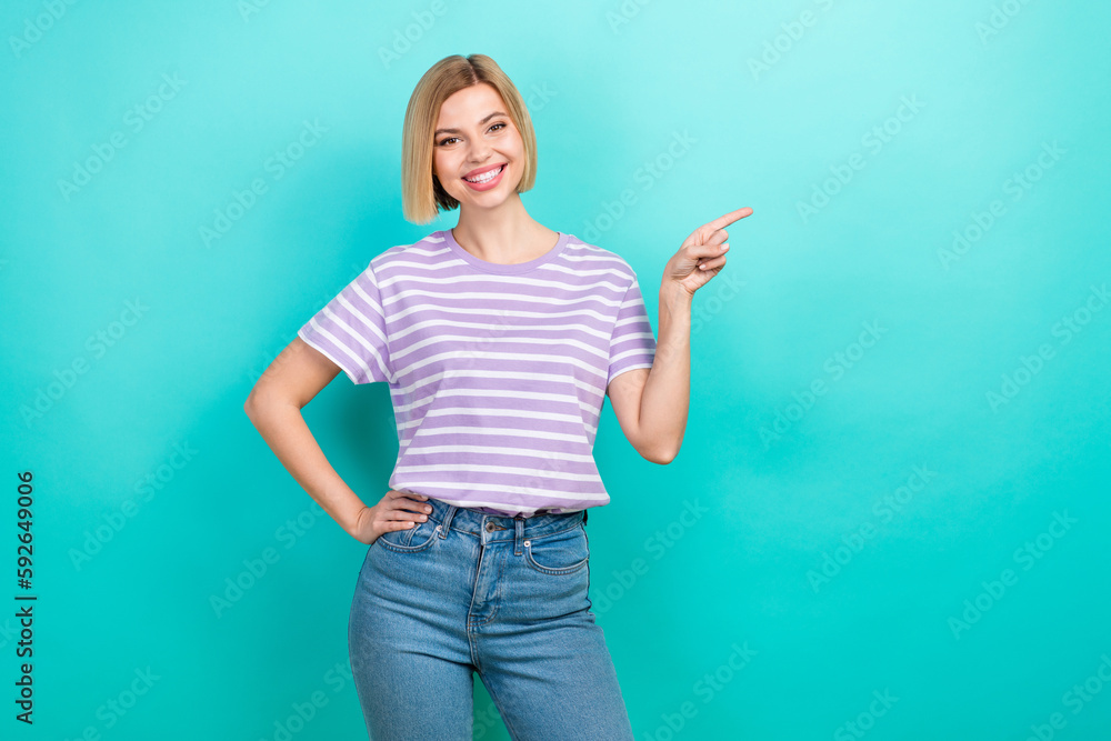 Portrait of pleasant cute woman with short haircut stylish t-shirt indicating empty space discount isolated on teal color background Portrait of pleasant cute woman with short haircut stylish t-shirt indicating empty space discount isolated on teal color background