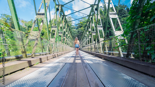 Pont suspendu métallique de Grand Rivière en Martinique avec une femme de dos, Antilles Françaises. photo