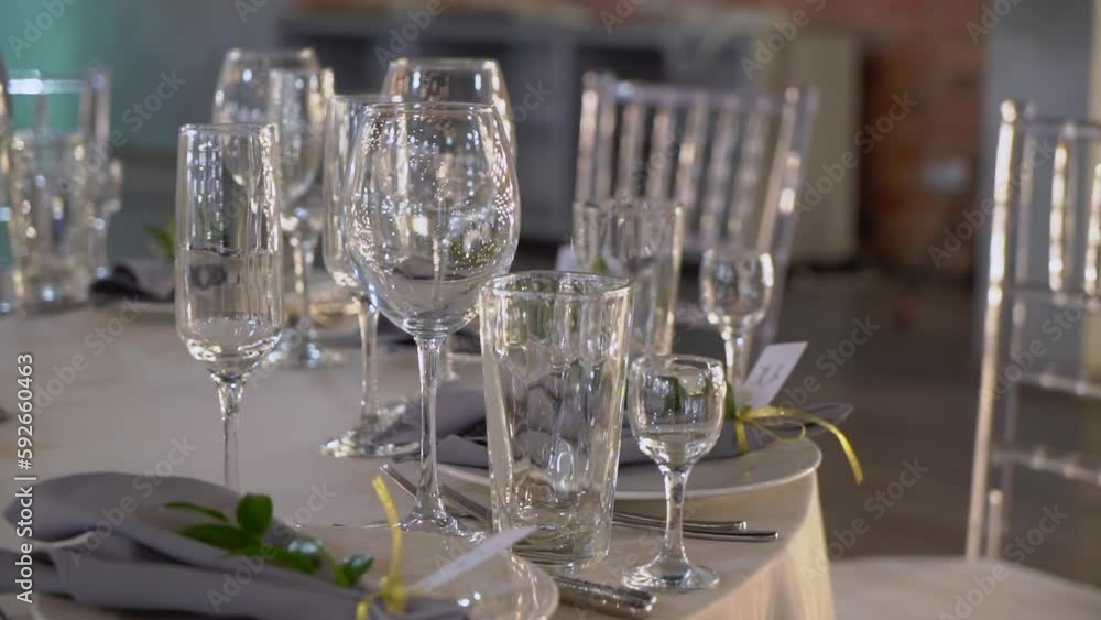 Served tables for a holiday in a restaurant. Glasses, plates, cutlery, napkins. Wedding decor, celebration dinner or party, reception indoors. No food. Decorated with flowers. Served tables for a holiday in a restaurant. Glasses, plates, cutlery, napkins. Wedding decor, celebration dinner or party, reception indoors. No food. Decorated with flowers.