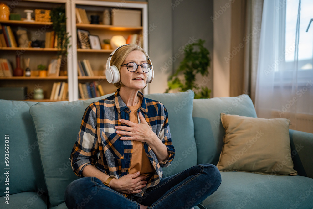 Obraz premium Mature senior woman practice guided meditation manifestation at home