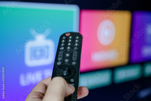 Controle de tv acionando para ligar e assistir series e filmes na televisão smart com fundo borrado.	