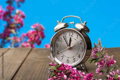 Alarm clock and  fresh spring flowers on table