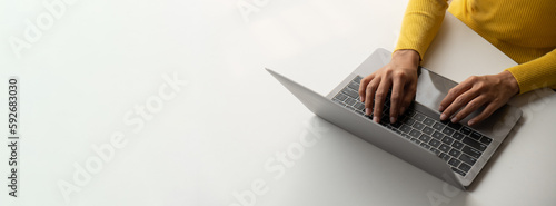Close up view of young woman working and typing on laptop computer at her desk.