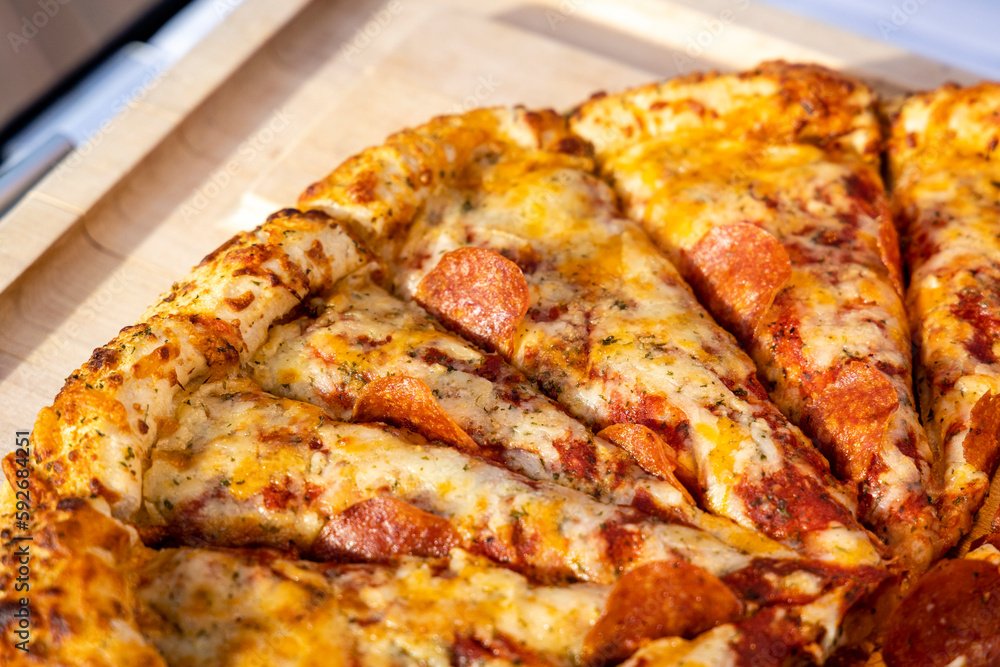 A closeup section of a pizza being Served in an outdoor setting for an event. A closeup section of a pizza being Served in an outdoor setting for an event.