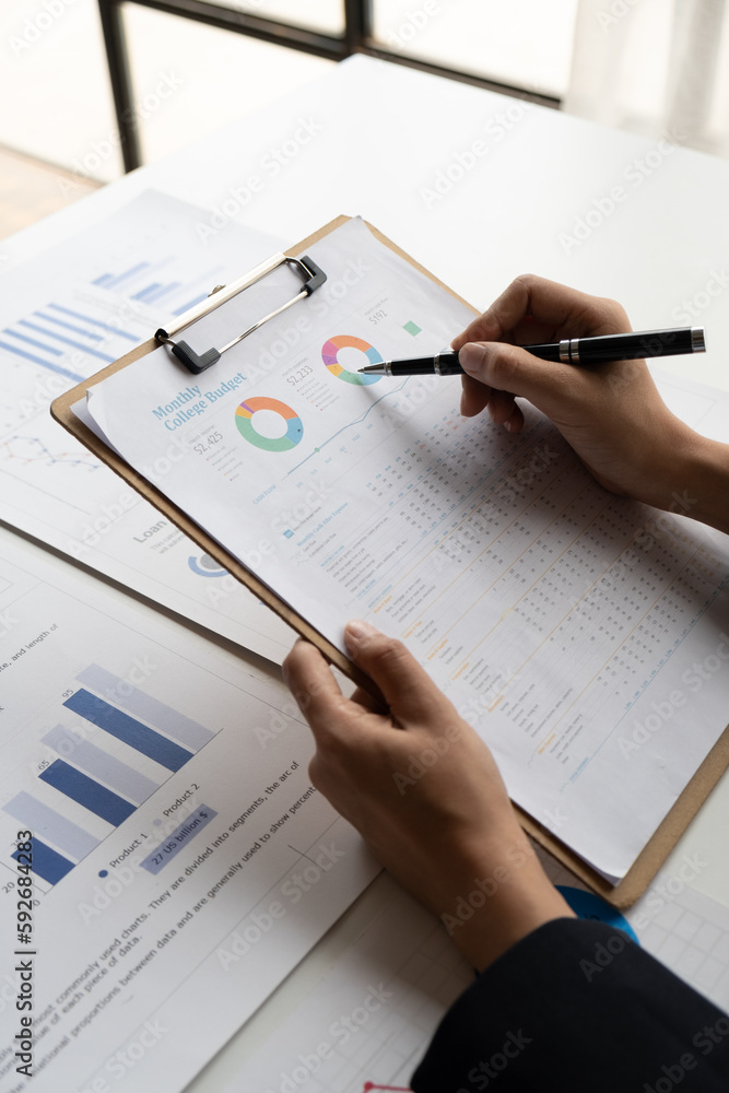 Close up view of young businesswoman working on her project with graph and charts, analyzing the business details. Close up view of young businesswoman working on her project with graph and charts, analyzing the business details.