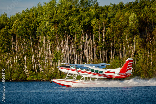 Cessna, 207 on floats taking off from the lake with forest in the background.
