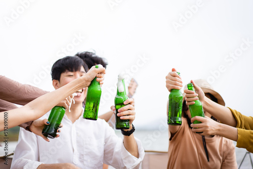 Group of Asian young adult people enjoy drinking a beer together during camping at the park. 