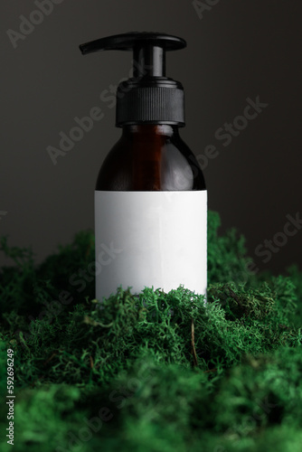 Mock up on dark glass bottle with dispenser of cosmetic product on green moss and black background. Organic body treatment, skin care, spa concept. Biophilia design. Vegan eco bio friendly cosmetology