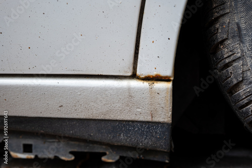 Rusted or rusting door sill of white-painted modern car. Close up shot, no people, bubbling paint