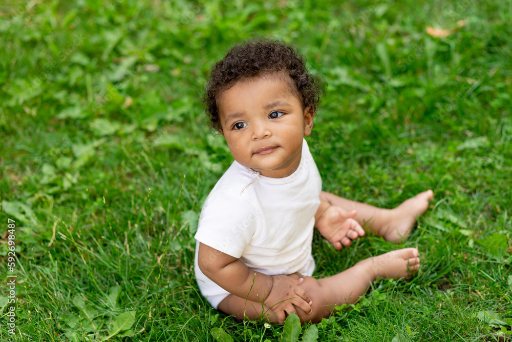 happy African-American baby boy on the green grass lawn in summer smiling, space for text happy African-American baby boy on the green grass lawn in summer smiling, space for text